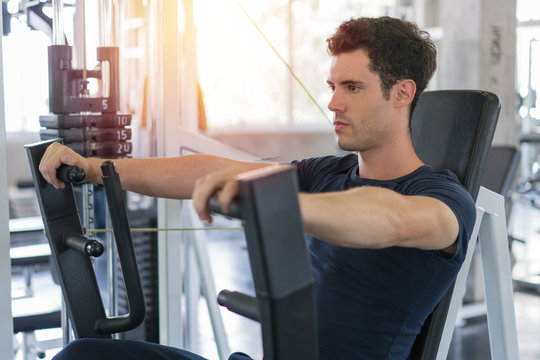 Handsome Man Lowering Weight Of Fitness Machine And Working Out In The Fitness Gym