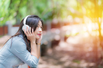 Young beautiful woman enjoying music in the garden listening to music with headphones