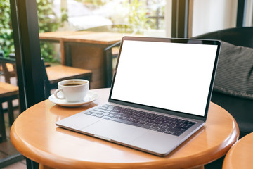 Mockup image of laptop computer with blank white desktop screen with coffee cup on wooden table