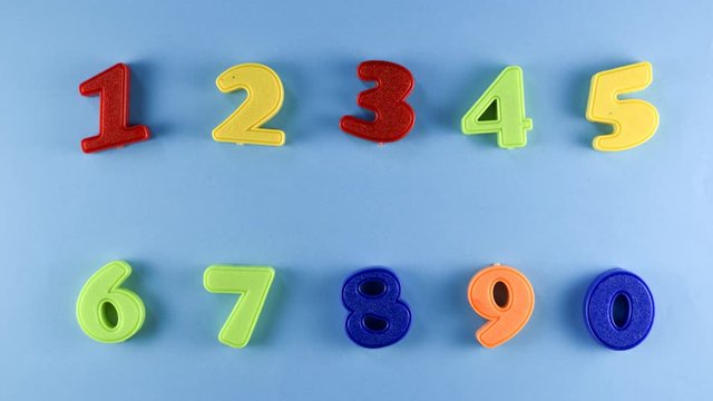 Stop Motion - Colorful plastic numbers wiggle or moving on a blue background. Concept of learning mathematics, numbers and counting. 4k mp4 high quality 