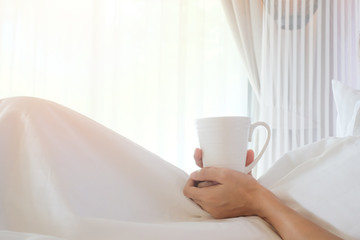 Fototapeta na wymiar Asia woman holding coffee on white bed, morning concept.