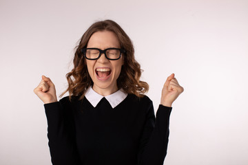 beautiful young woman in a school dress and glasses shouting and holding her head on a white background