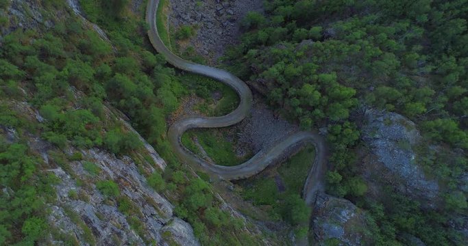 Aerial: Drone moving up over winding road by trees - Borgund, Norway