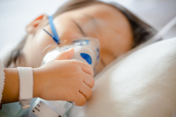 Naklejka premium Little Asian girl is sick in a bed with an oxygen mask in hospital