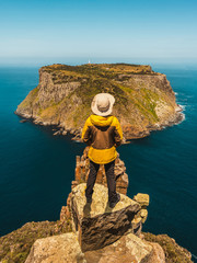 Young man trekker hiking on beautiful coast cliff of Tasman National Park in Tasman peninsula, Three Capes Track near Port Arthur in Tasmania, Australia. - obrazy, fototapety, plakaty
