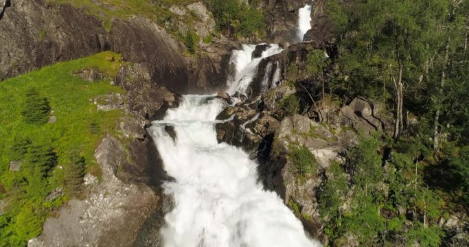Aerial: Drone ascending over waterfall flowing from mountain - Borgund, Norway