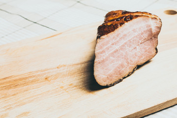 Large piece of smoked boar meat on wooden cutting board.