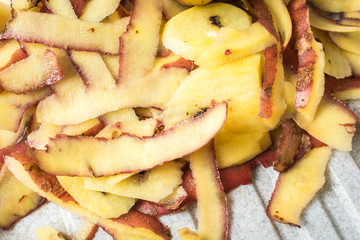 Purified skin of collected potatoes with special knife on sink.