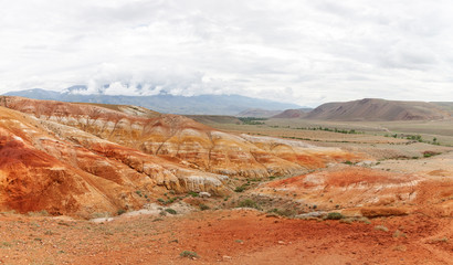 A stunning panorama of a mountain chain of peaks, a canyon with red clay, top view. Mars fields in Altai, Russia. fantastic clay castles in the sandy desert of the red canyon