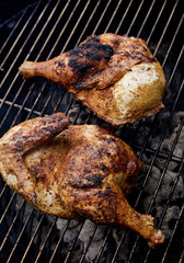 Closeup of seasoned chicken cooking over hot charcoal grill