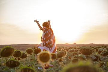 a girl holds an American flag at sunset .