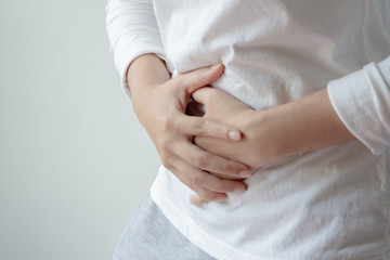 Young woman with white t-shirt suffering from abdominal pain.Chronic gastritis or abdomen bloating and healthcare concept.