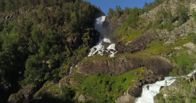 Aerial: Drone approaching over waterfall flowing through rocks with spectrum appearance - Borgund, Norway