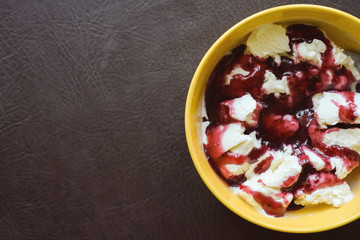 close up. a vanilla ice cream topped with fresh red berries. Delicious summer dessert on a yellow plate. Delicacy. Goodbye diet. Junk food.