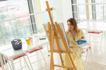 Art class and drawing concept - Woman artist working on painting in studio.