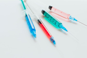  syringes with multicolored liquid on a white background.