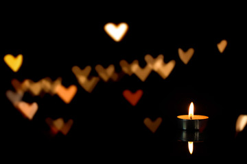 burning candle and heart shaped bokeh