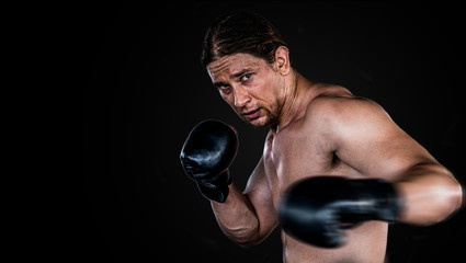 Fototapeta na wymiar Muscular man boxing with gloves. boxer punching fist movement . Isolated on black background with copy Space.