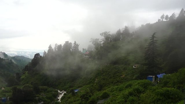 Panning shot of clouds going over the mountains on the bhagsu falls in McLeodganj, Dharamshala India
