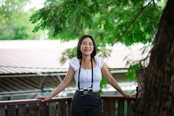 Asian woman with big smile carrying vintage film camera