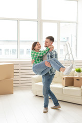 Fototapeta na wymiar Loving young couple embracing rejoicing in moving to their new home. The concept of moving and housewarming of young family.