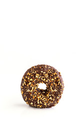 Close up of chocolate glazed donut with nuts on white background. Copy space
