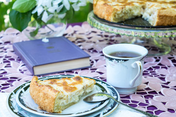 Breakfast in the garden. Apple pie and tea in a cup on a beautiful lace tablecloth under blooming apple trees.