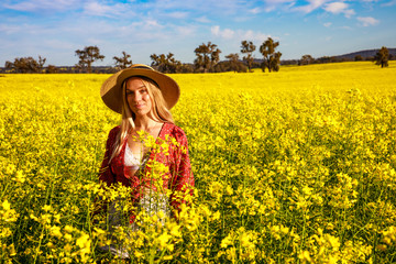 Fototapeta premium Happy young lady with straw hat in yellow Canola Field in Western Australia