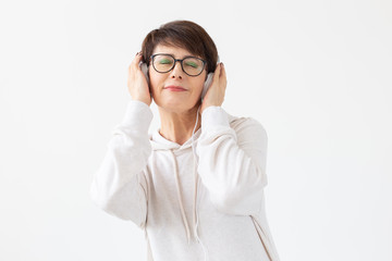 Beautiful woman 40-50 years old listening music in big headphone on white background with copy space