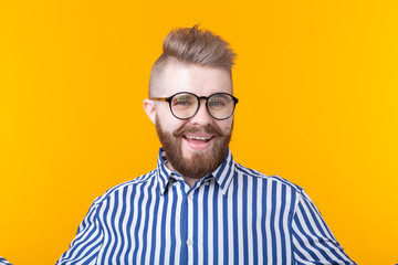 Obraz premium Young positive trendy man hipster with a mustache beard in shirt posing on a yellow background.