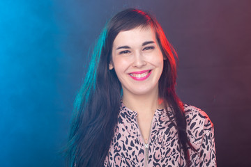 Fototapeta premium Cheerful funny young brunette woman with long hair posing on colourful background. The concept of a beautiful and well-groomed woman