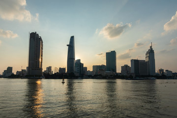Obraz premium skyline view from the river. Vietnamese City with modern building, high rise Relection on water of Asiatic Metropolis of Saigon know also as Ho Chi Minh city, South Vietnam.