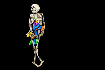Human like rubber skeleton with colored pills inside it , conceptual image about health , illness and pharmaceutical industry