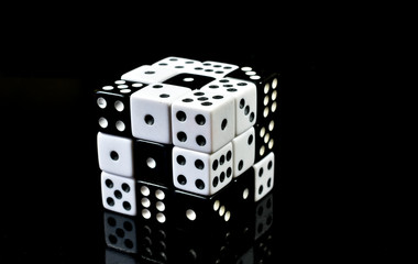 Cube made of smaller black and white dice , with reflection on black background , conceptual image