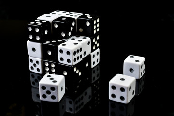 Cube made from smaller black and white dice  , three of them being removed and place on a black surface , conceptual image