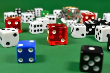Multiple colored dice in close up view , placed on a green surface