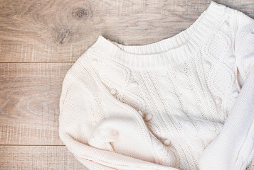 White knitted sweater on a wooden grey table, top view. Flat lay, copy space