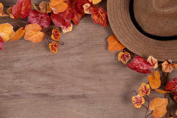 Flat lay top view of rustic wooden background decorated with colorful maple autumn leaves autumn style concept with scarf, brown vintage hat and coffee cup with latte art