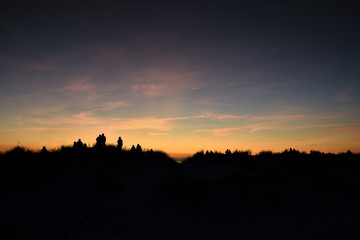 Silhouettes on dunes by Baltic sea in sunset time.