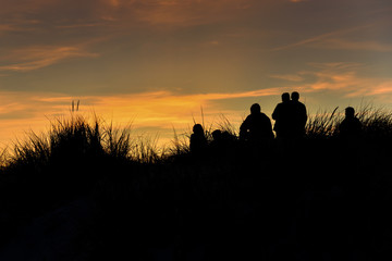 Fototapeta na wymiar Silhouettes on dunes by Baltic sea in sunset time.