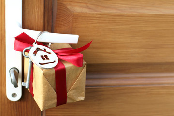 gift with house and key symbols hanging on a doorknob. holiday surprise for the new year