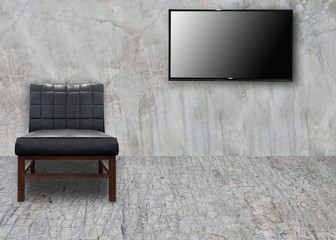 Vintage black leather chair interior in the room with lcd tv on concrete wall background.