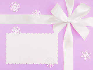 White bow, snowflakes, place for an inscription on a lilac background. Christmas and New Year concept