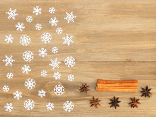 Brown wooden Christmas background with snowflakes, cinnamon, anise. Christmas and New Year concept
