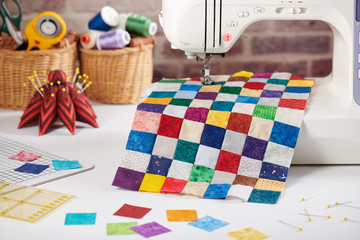 Colorful detail of quilt sewn from square pieces on sewing machine, quilting and sewing accessories