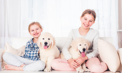 Smiling sisters sitting with puppies