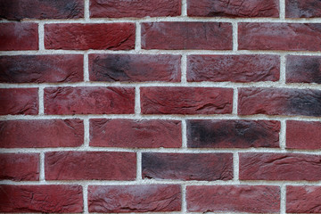 Background of red and black spotted old brick with a white cement seam. Grunge pattern texture.