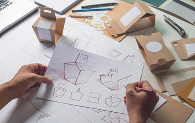 Designer sketching drawing design Brown craft cardboard paper product eco packaging mockup box development template package branding Label . designer studio concept .