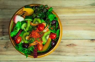 Top view various fresh healthy mixed vegetables salad with flyinh fish roe on top in wooden bowl.