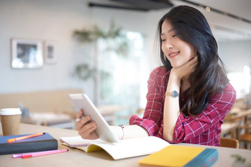 Young Asian woman using laptop computer and tablet PC to working in the modern co working space 